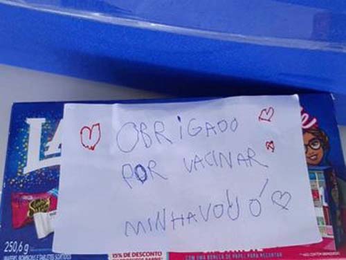 Criança leva caixa de chocolate e cartinha a local de vacinação para agradecer por imunização da avó