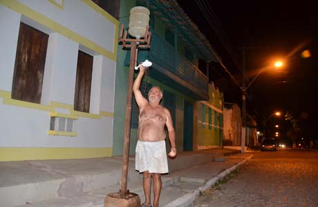 Ancião improvisa chuveiro na porta de casa após corte do SAAE em Marechal Deodoro